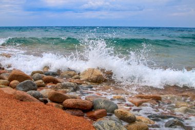 Su dalgası sıçramalarına, bir açık mavi gökyüzü arka plan. Bir güzel mavi dağ göl kıyısında taş yuvarlak. Yaz, turizm. Saf mavi su, açık gökyüzü, su sıçramalarına, dalgalar.