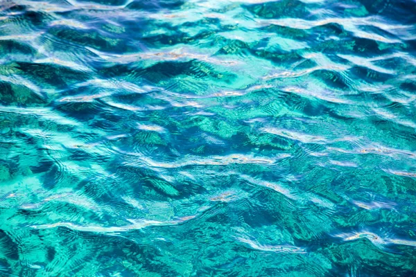 El arrecife de coral es visible a través del agua azul clara. Hermosa fotografía de onda azul del mar de cerca. Vacaciones en la playa en el mar o el océano. Fondo para insertar imágenes y texto. Turismo, viajes . — Foto de Stock