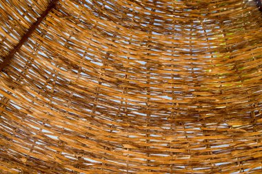 Hasır çatı plaj şemsiyesi. Mavi gökyüzü görebilirsiniz üzerinden hasır twigs doku. Kahverengi renk. Doğal arka plan.