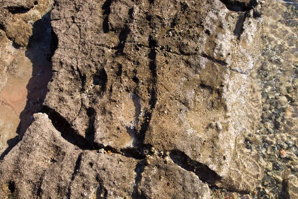 Costa de piedra. Rocas y agua. Fondo natural. Textura de piedra del borde del agua — Foto de Stock