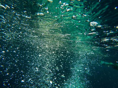 Suyun altındaki hava kabarcıkları yükselir. Deniz ve okyanus suyunun güzel dokusu. Hava mavisi arka plan. Sualtı fotoğrafçılığı.