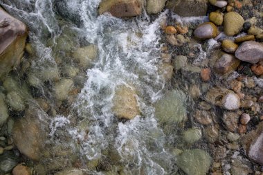 Azgın nehirdeki su. Taşların ve suyun güzel doğal arka planı. Berrak su ve hızlı nehir dokusu. Metin eklemek için arka plan. Turizm ve seyahat.
