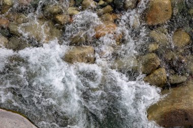 Azgın nehirdeki su. Taşların ve suyun güzel doğal arka planı. Berrak su ve hızlı nehir dokusu. Metin eklemek için arka plan. Turizm ve seyahat.