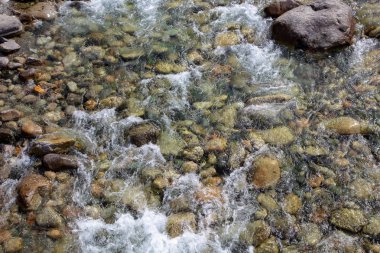 Azgın nehirdeki su. Taşların ve suyun güzel doğal arka planı. Berrak su ve hızlı nehir dokusu. Metin eklemek için arka plan. Turizm ve seyahat.