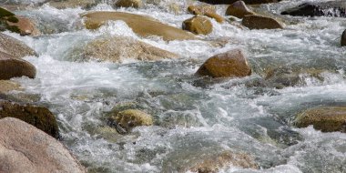 Azgın nehirdeki su. Taşların ve suyun güzel doğal arka planı. Berrak su ve hızlı nehir dokusu. Metin eklemek için arka plan. Turizm ve seyahat.