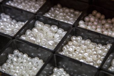 farklı kutularda inci boncuklar. El yapımı mücevher için malzeme. Mağaza ve usta için arka plan. Yaratıcılık için alışveriş yapın. Kadınların moda zanaat.