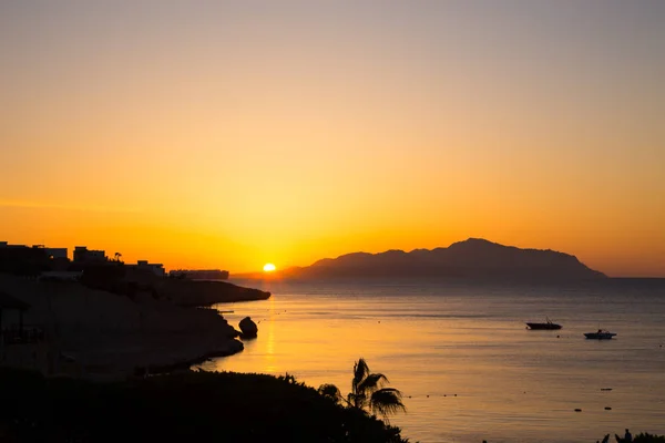 Salida del sol sobre el mar rojo. Hermoso cielo brillante con rayos de sol y nubes de la mañana. Mar y barcos. Vista de la isla Tiran. Egipto, Sharm El Sheikh. Turismo y viajes . — Foto de Stock