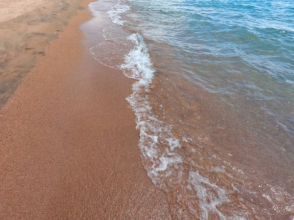 A textura de água clara com fundo arenoso. Onda na praia ou no oceano. Fundo natural natural . — Fotografia de Stock