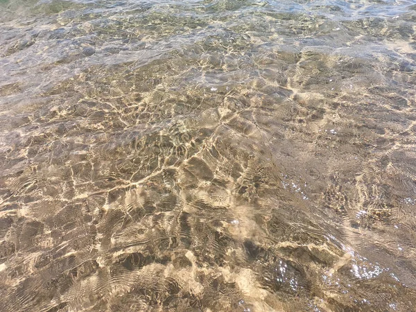 La textura del agua clara con fondo arenoso. Fondo natural natural. Turismo y viajes —  Fotos de Stock