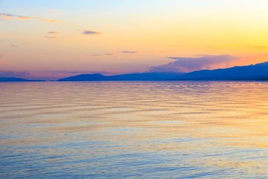 Dağlardaki bir gölde güzel gün batımı. Kırgızistan, İssyk-Kul Gölü. Parlak gökyüzü, sıcak renklerde arka plan.