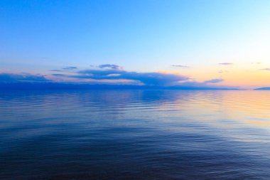 Dağlardaki bir gölde güzel gün batımı. Kırgızistan, İssyk-Kul Gölü. Parlak gökyüzü, sıcak renklerde arka plan.