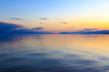 Dağlardaki bir gölde güzel gün batımı. Kırgızistan, İssyk-Kul Gölü. Parlak gökyüzü, sıcak renklerde arka plan.