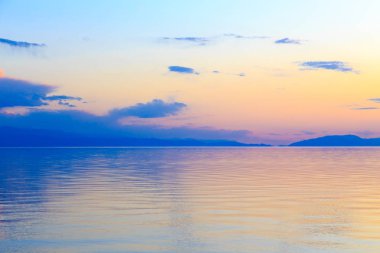 Dağlardaki bir gölde güzel gün batımı. Kırgızistan, İssyk-Kul Gölü. Parlak gökyüzü, sıcak renklerde arka plan.