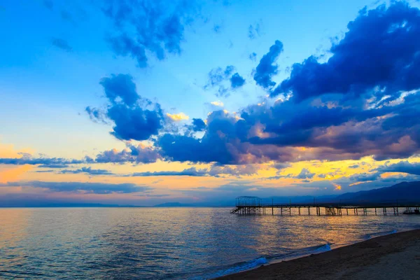 Hermosa puesta de sol en un lago en las montañas. Kirguistán, lago Issyk-Kul. Cielo brillante, fondo en colores cálidos . — Foto de Stock