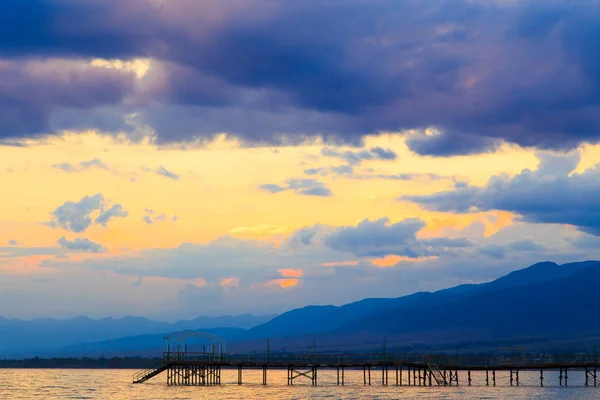 Belo pôr-do-sol num lago nas montanhas. Quirguizistão, Lago Issyk-Kul. Céu brilhante, fundo em cores quentes . — Fotografia de Stock