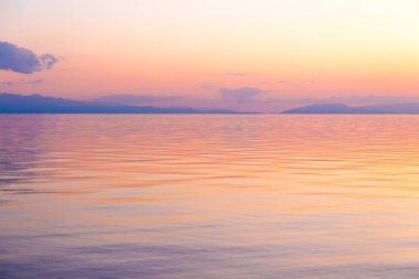 Dağlardaki bir gölde güzel gün batımı. Kırgızistan, İssyk-Kul Gölü. Parlak gökyüzü, sıcak renklerde arka plan.