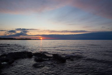 Dağlardaki bir gölde güzel gün batımı. Kırgızistan, İssyk-Kul Gölü. Parlak gökyüzü, sıcak renklerde arka plan.
