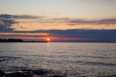 Dağlardaki bir gölde güzel gün batımı. Kırgızistan, İssyk-Kul Gölü. Parlak gökyüzü, sıcak renklerde arka plan.
