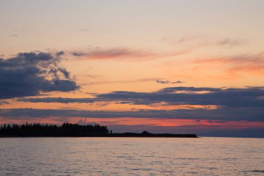 Dağlardaki bir gölde güzel gün batımı. Kırgızistan, İssyk-Kul Gölü. Parlak gökyüzü, sıcak renklerde arka plan.