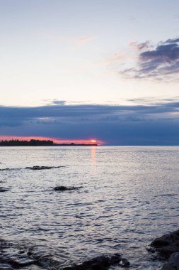 Dağlardaki bir gölde güzel gün batımı. Kırgızistan, İssyk-Kul Gölü. Parlak gökyüzü, sıcak renklerde arka plan.
