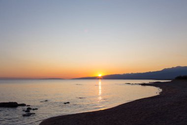 Dağlardaki bir gölde güzel gün batımı. Kırgızistan, İssyk-Kul Gölü. Parlak gökyüzü, sıcak renklerde arka plan.