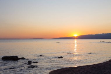 Dağlardaki bir gölde güzel gün batımı. Kırgızistan, İssyk-Kul Gölü. Parlak gökyüzü, sıcak renklerde arka plan.