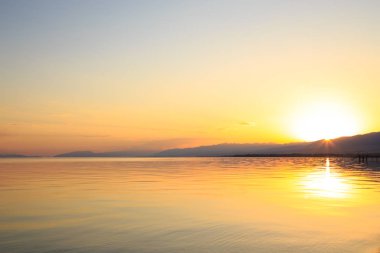 Dağlardaki bir gölde güzel gün batımı. Kırgızistan, İssyk-Kul Gölü. Parlak gökyüzü, sıcak renklerde arka plan.
