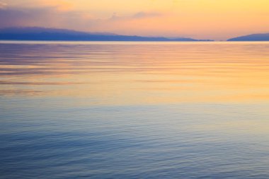 Dağlardaki bir gölde güzel gün batımı. Kırgızistan, İssyk-Kul Gölü. Parlak gökyüzü, sıcak renklerde arka plan.