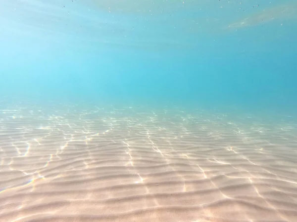 Agua clara. fondo submarino con fondo marino arenoso. Hermosa textura del mar y el agua del océano . — Foto de Stock