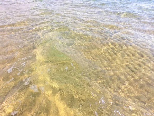 La texture dell'acqua limpida con fondo sabbioso. Onda sulla riva del mare o sull'oceano . — Foto Stock