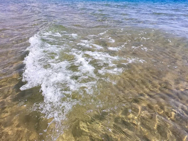 La texture dell'acqua limpida con fondo sabbioso. Onda sulla riva del mare o sull'oceano . — Foto Stock