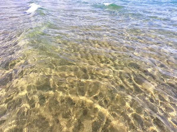 Die Textur des klaren Wassers mit sandigem Boden. Welle an der Küste oder auf dem Ozean. — Stockfoto