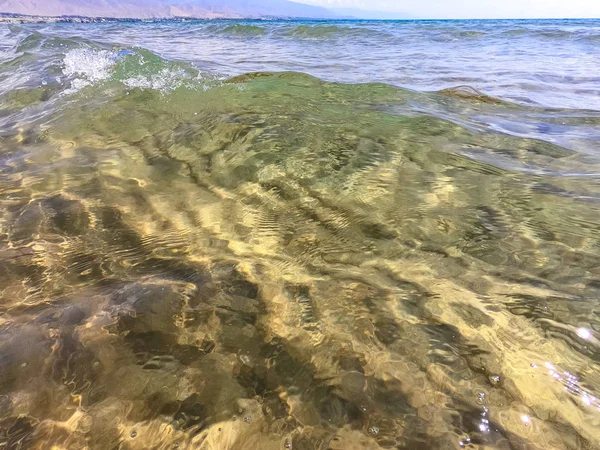 Tekstura przezroczystej wody z piaszczystym dnem. Fala na brzegu morza lub oceanu. — Zdjęcie stockowe