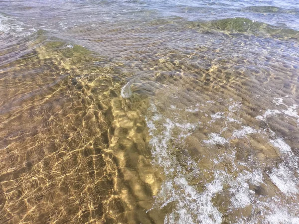 Die Textur des klaren Wassers mit sandigem Boden. Welle an der Küste oder auf dem Ozean. — Stockfoto