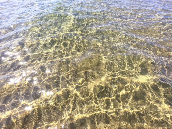 La textura del agua clara con fondo arenoso. Ola en la orilla del mar o el océano . — Foto de Stock