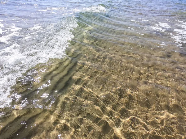 Tekstura przezroczystej wody z piaszczystym dnem. Fala na brzegu morza lub oceanu. — Zdjęcie stockowe