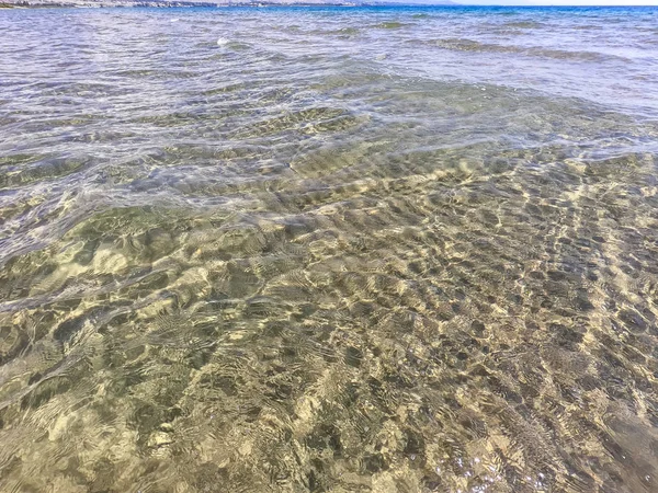 La textura del agua clara con fondo arenoso. Ola en la orilla del mar o el océano . — Foto de Stock