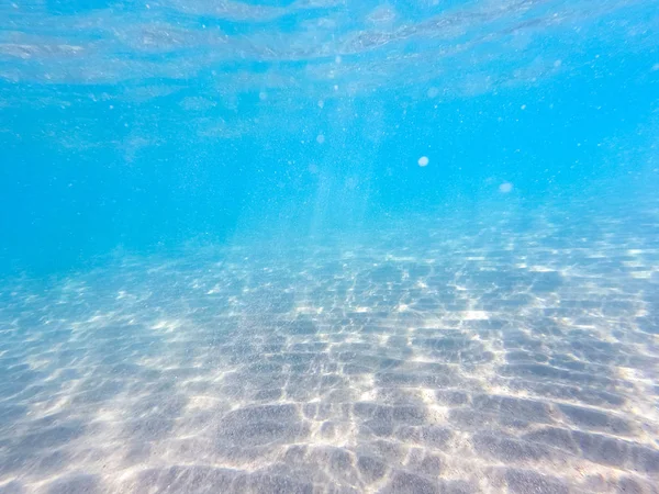 Agua clara. fondo submarino con fondo marino arenoso. Hermosa textura del mar y el agua del océano . — Foto de Stock