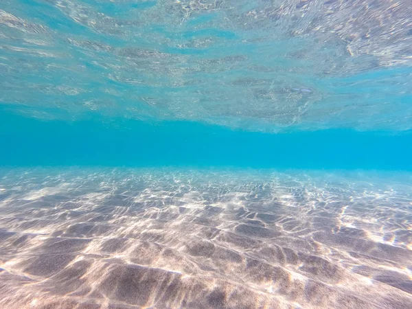 Agua clara. fondo submarino con fondo marino arenoso. Hermosa textura del mar y el agua del océano . — Foto de Stock