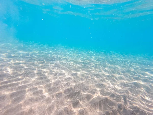 Agua clara. fondo submarino con fondo marino arenoso. Hermosa textura del mar y el agua del océano . — Foto de Stock