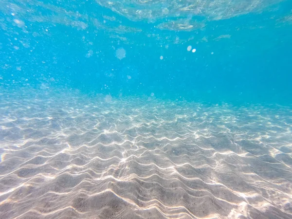 Agua clara. fondo submarino con fondo marino arenoso. Hermosa textura del mar y el agua del océano . — Foto de Stock