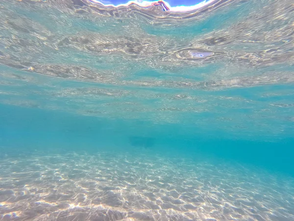 Agua clara. fondo submarino con fondo marino arenoso. Hermosa textura del mar y el agua del océano . — Foto de Stock