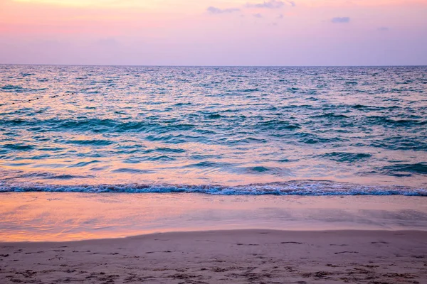 Tramonto sul mare. spiaggia sabbiosa, acqua limpida, onde. surf line nei colori caldi del sole al tramonto . — Foto Stock