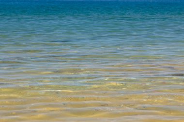 Mavi ve turuncu berrak su dokusu. Okyanusun arka planı ve güneş tarafından aydınlatılan deniz. Yumuşak dalgalar. Doğal su.