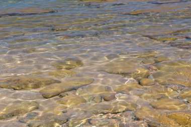 Mavi ve turuncu berrak su dokusu. Okyanusun arka planı ve güneş tarafından aydınlatılan deniz. Yumuşak dalgalar. Doğal su.