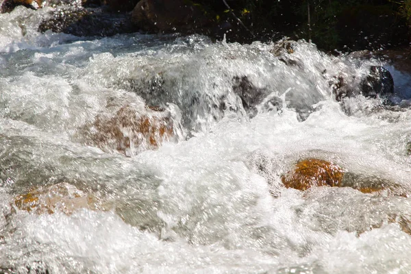 Vatten i den rasande floden. Vacker naturlig bakgrund av stenar och vatten. Textur av klart vatten och snabb flod. — Stockfoto