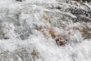 Dağdaki azgın nehirde su. Taş ve suyun güzel doğal arka planı. Temiz su ve hızlı nehir dokusu.