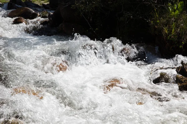 Vatten i den rasande floden. Vacker naturlig bakgrund av stenar och vatten. Textur av klart vatten och snabb flod. — Stockfoto