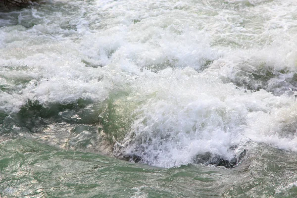 Vatten i den rasande floden. Vacker naturlig bakgrund av stenar och vatten. Textur av klart vatten och snabb flod. — Stockfoto