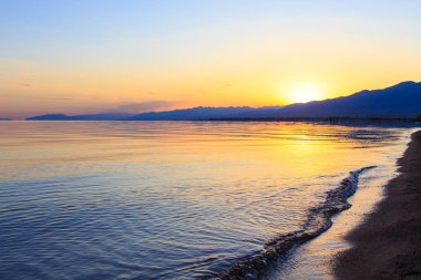 Mavi ve turuncu berrak su dokusu. Okyanusun arka planı ve güneş tarafından aydınlatılan deniz. Yumuşak dalgalar. Doğal su.